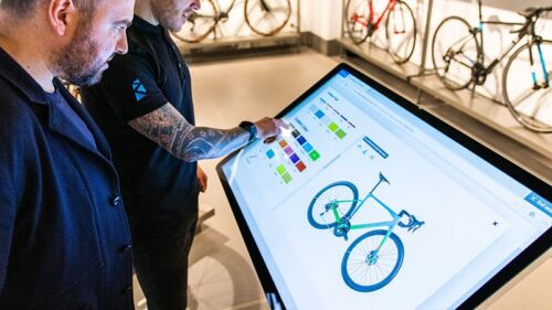 Customers using freestanding touchscreen kiosk in bike store